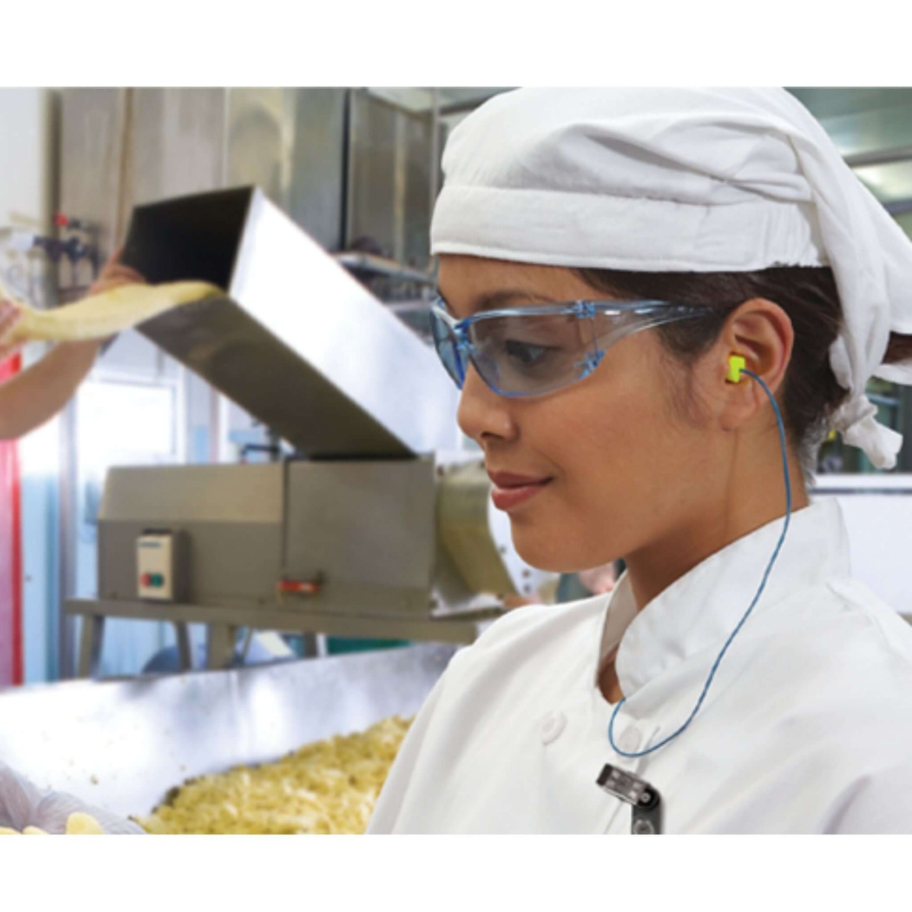 Woman in a kitchen wearing earplugs, demonstrating how to choose the best earplugs for sleep, work, and travel.
